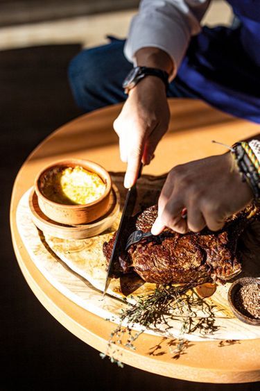 Au Bazurto, à Tignes, le chef colombien Juan Arbelaez découpe une pièce de bœuf cuite à la braise, à tremper dans un mont-d’or au four.